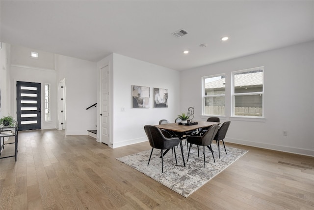 dining space with baseboards, visible vents, light wood finished floors, and stairway