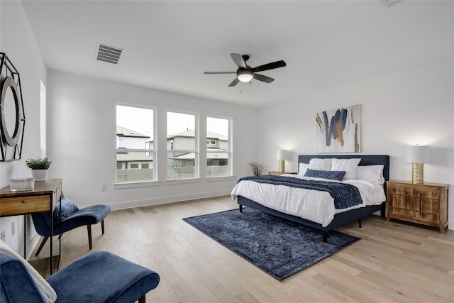 bedroom with a ceiling fan, baseboards, visible vents, and wood finished floors