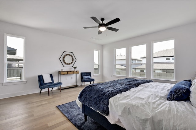 bedroom featuring baseboards, visible vents, ceiling fan, and light wood finished floors