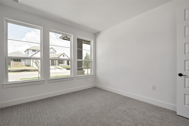 carpeted empty room featuring baseboards