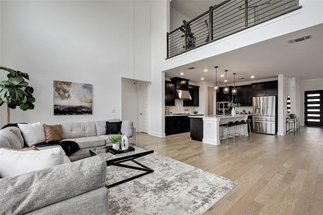 living room with recessed lighting, a high ceiling, visible vents, and light wood-type flooring