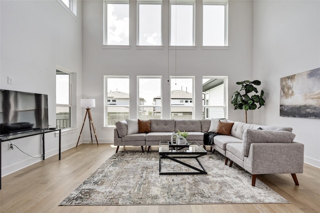 living area with baseboards, wood finished floors, and a towering ceiling