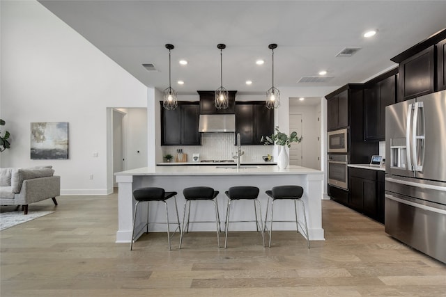 kitchen featuring under cabinet range hood, appliances with stainless steel finishes, visible vents, and light wood-style floors