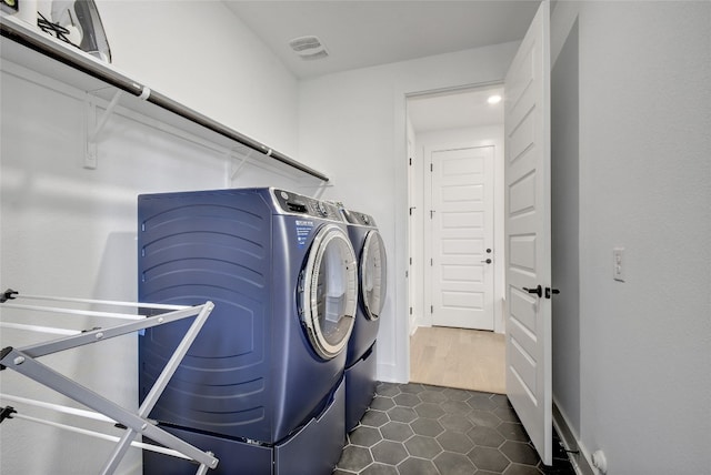 clothes washing area with laundry area, washing machine and dryer, and dark tile patterned flooring