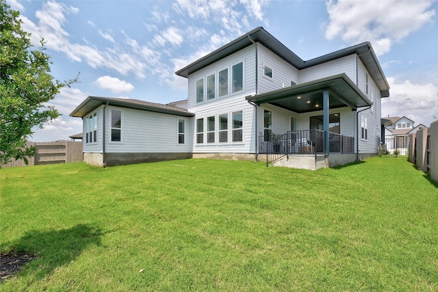 rear view of house featuring a lawn and a fenced backyard