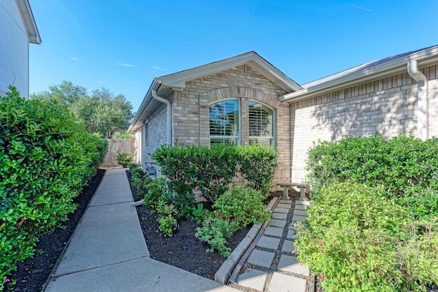 view of property exterior featuring brick siding and fence