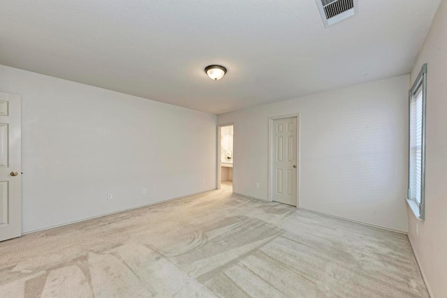 empty room with light colored carpet, plenty of natural light, and visible vents