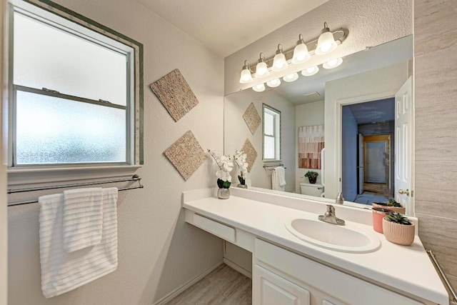 bathroom featuring a healthy amount of sunlight, vanity, baseboards, and toilet