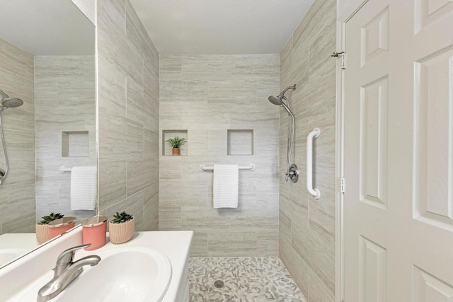 full bath featuring vanity, tile walls, and tiled shower