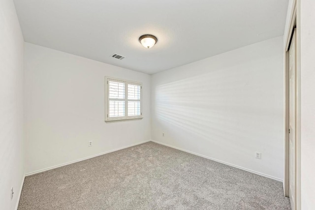 carpeted spare room with visible vents and baseboards