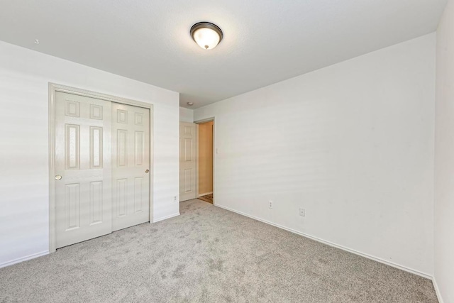unfurnished bedroom featuring carpet floors, baseboards, and a closet
