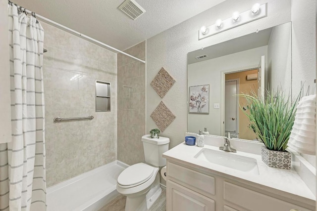 bathroom with vanity, toilet, a textured ceiling, visible vents, and tiled shower