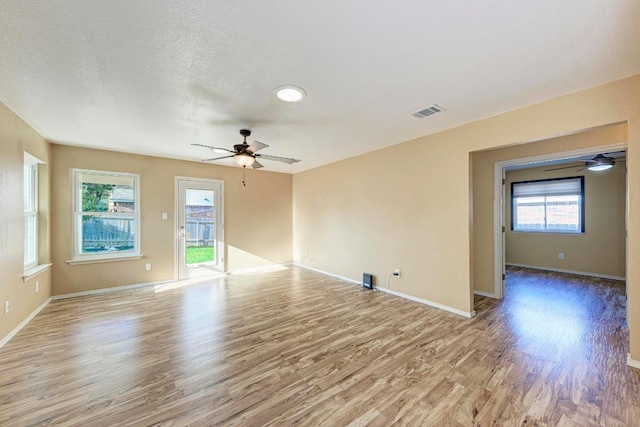 unfurnished room featuring visible vents, a ceiling fan, light wood-style floors, and baseboards