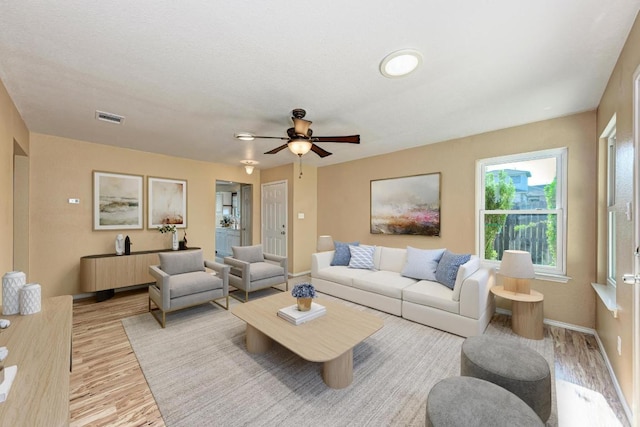 living room with a ceiling fan, baseboards, visible vents, and light wood-style floors