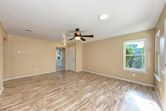 empty room featuring a ceiling fan, baseboards, visible vents, and light wood-style flooring