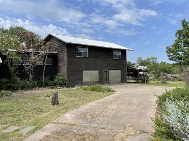 401 County Road 128, Burnet, TX 78611 - view of home's exterior with an attached garage, a lawn, metal roof, and concrete driveway