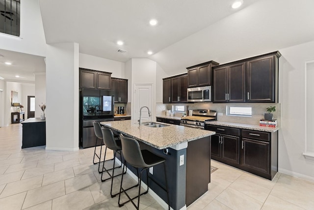 kitchen featuring light stone countertops, a kitchen bar, tasteful backsplash, a sink, and stainless steel appliances