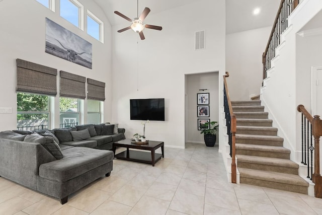 living room featuring ceiling fan, visible vents, a towering ceiling, stairway, and baseboards