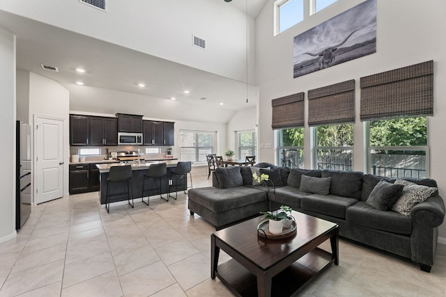 living room featuring high vaulted ceiling, visible vents, and a healthy amount of sunlight