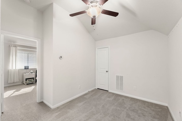 interior space featuring light colored carpet, a ceiling fan, baseboards, lofted ceiling, and visible vents
