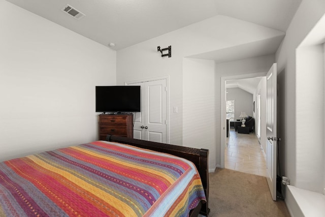 bedroom with visible vents, light colored carpet, and lofted ceiling