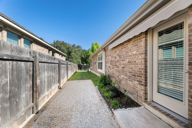 view of property exterior featuring brick siding, a fenced backyard, and a patio area