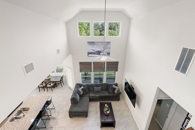 living room featuring visible vents, ceiling fan, light tile patterned flooring, and high vaulted ceiling