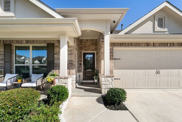 view of exterior entry with covered porch, stone siding, brick siding, concrete driveway, and an attached garage
