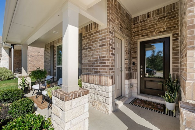 property entrance featuring brick siding and covered porch