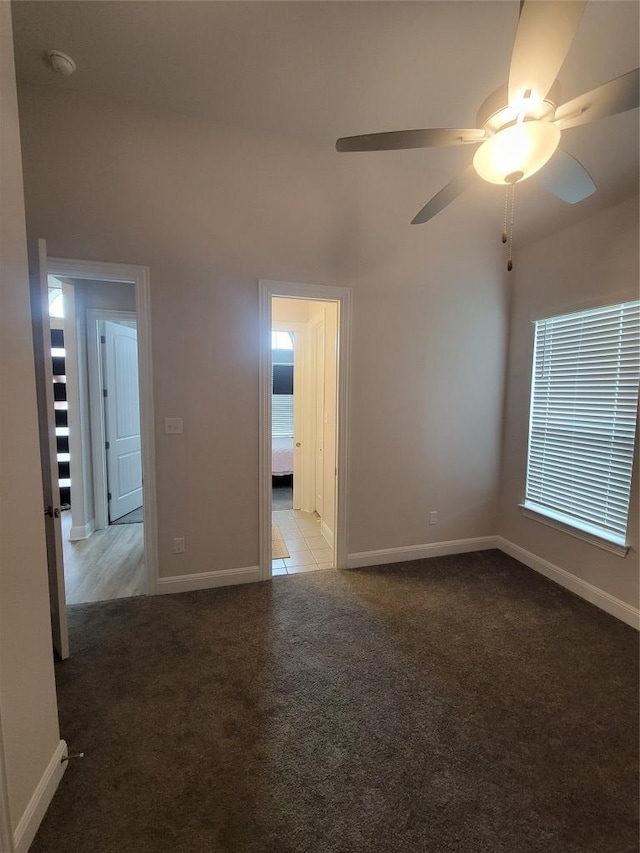 carpeted empty room with baseboards and a ceiling fan