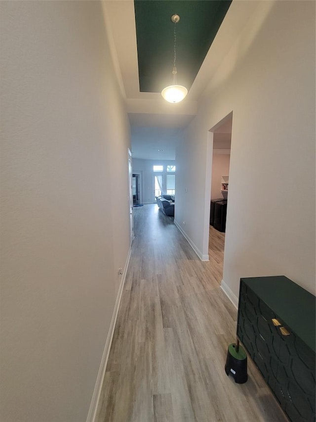 corridor featuring baseboards and light wood finished floors