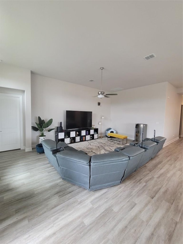 living area featuring baseboards, ceiling fan, wood finished floors, and visible vents