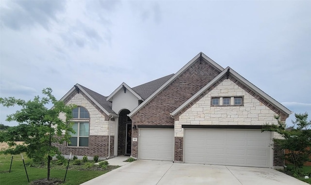 traditional-style house with concrete driveway, an attached garage, and stone siding