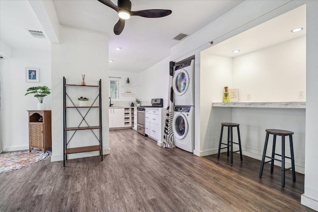 laundry room with visible vents, laundry area, dark wood-type flooring, and stacked washer / drying machine