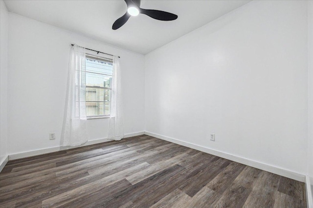spare room with baseboards, a ceiling fan, and dark wood-type flooring