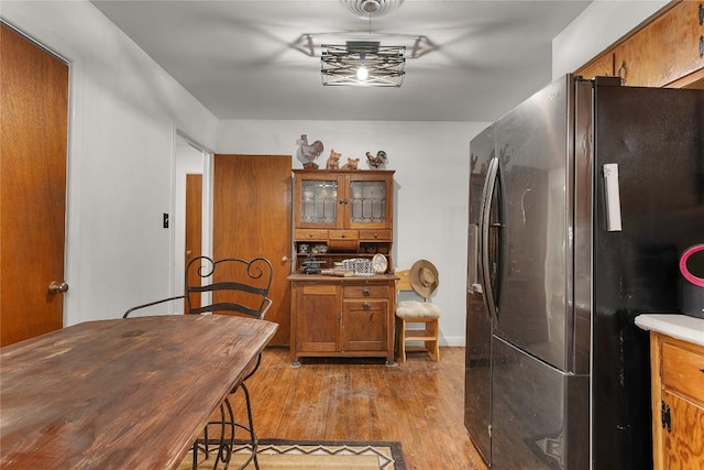 607 Gilmore St, Taylor, TX 76574 - kitchen with freestanding refrigerator, brown cabinetry, and light wood-type flooring