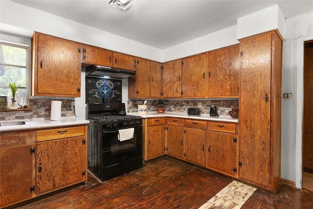 607 Gilmore St, Taylor, TX 76574 - kitchen featuring backsplash, brown cabinetry, black range with gas stovetop, and under cabinet range hood