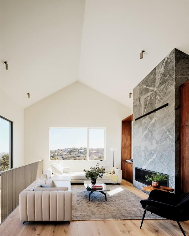 2405 Deer Pass, Austin, TX 78746 - living room with plenty of natural light, light wood-style flooring, high vaulted ceiling, and a tile fireplace