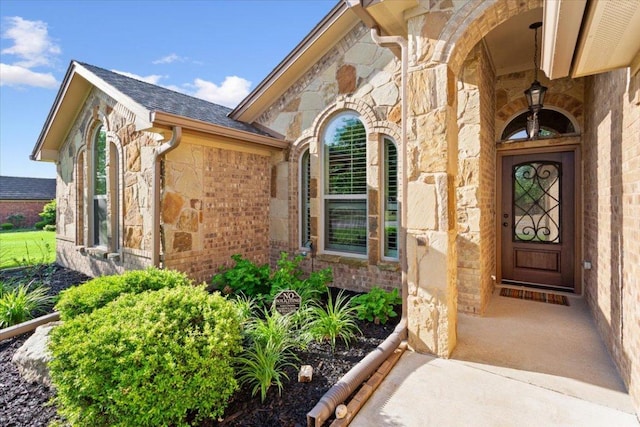 view of exterior entry with brick siding and stone siding