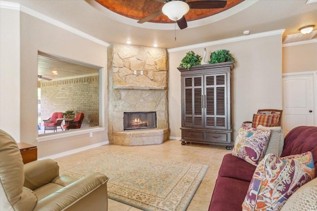 living area with ceiling fan, ornamental molding, and a stone fireplace