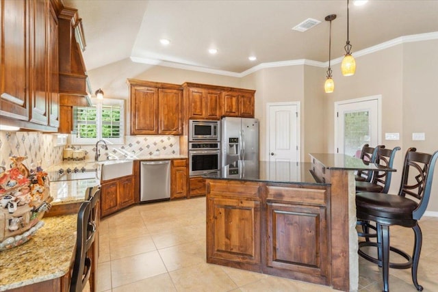kitchen featuring visible vents, appliances with stainless steel finishes, tasteful backsplash, a sink, and a breakfast bar
