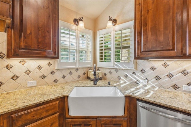 kitchen with stainless steel dishwasher, light stone counters, decorative backsplash, and a sink