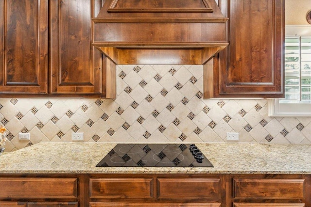 kitchen featuring light stone counters, tasteful backsplash, and black electric cooktop