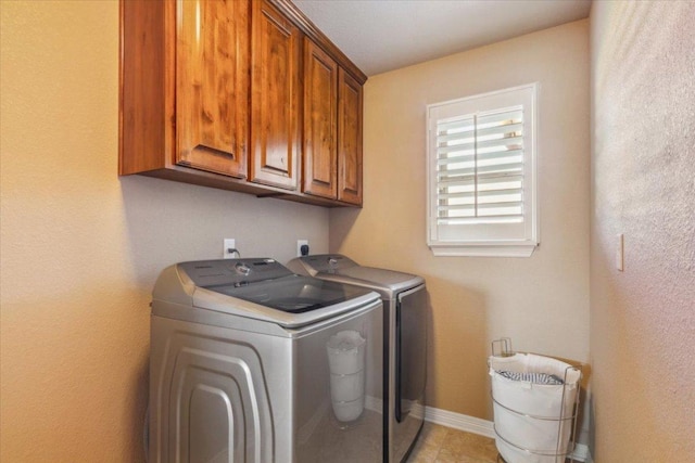 laundry area featuring baseboards, cabinet space, washing machine and dryer, and light tile patterned flooring