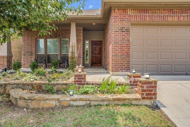 182 Lone Tree Holw, Buda, TX 78610 - property entrance featuring brick siding, covered porch, an attached garage, and concrete driveway