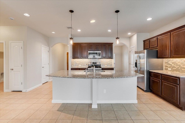 182 Lone Tree Holw, Buda, TX 78610 - kitchen with appliances with stainless steel finishes, arched walkways, tasteful backsplash, recessed lighting, and light stone counters