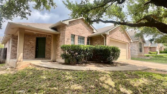 single story home featuring an attached garage, driveway, and brick siding
