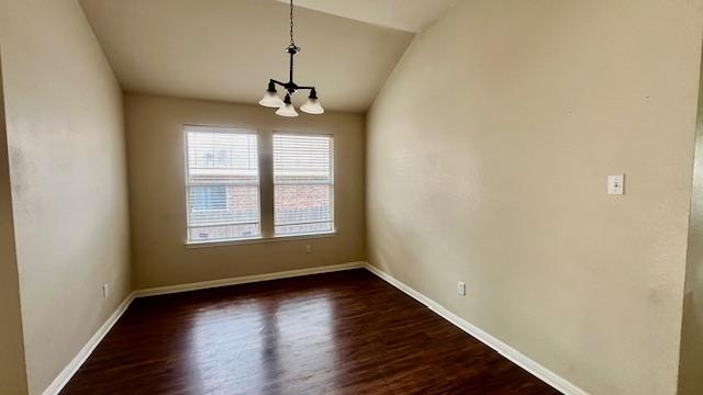 unfurnished room with an inviting chandelier, baseboards, dark wood finished floors, and lofted ceiling