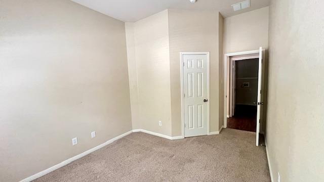empty room with baseboards, carpet flooring, and visible vents