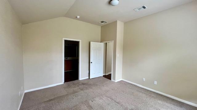 unfurnished bedroom with visible vents, baseboards, lofted ceiling, and carpet
